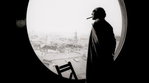 Jean-Luc Godard schaut durch ein rundes Fenster